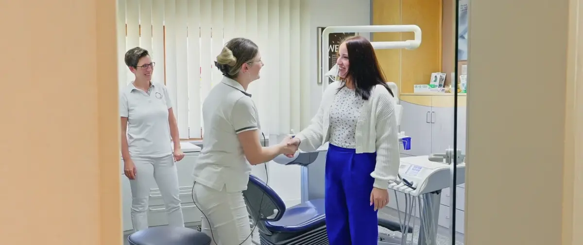 Aufnahme von Zahnärztin Sarah Knefel und Assistentin bei der freundlichen Begrüßung einer Patientin