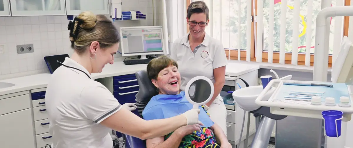 Aufnahme von Zahnärztin Sarah Knefel, Assistentin und lächelnder Patientin